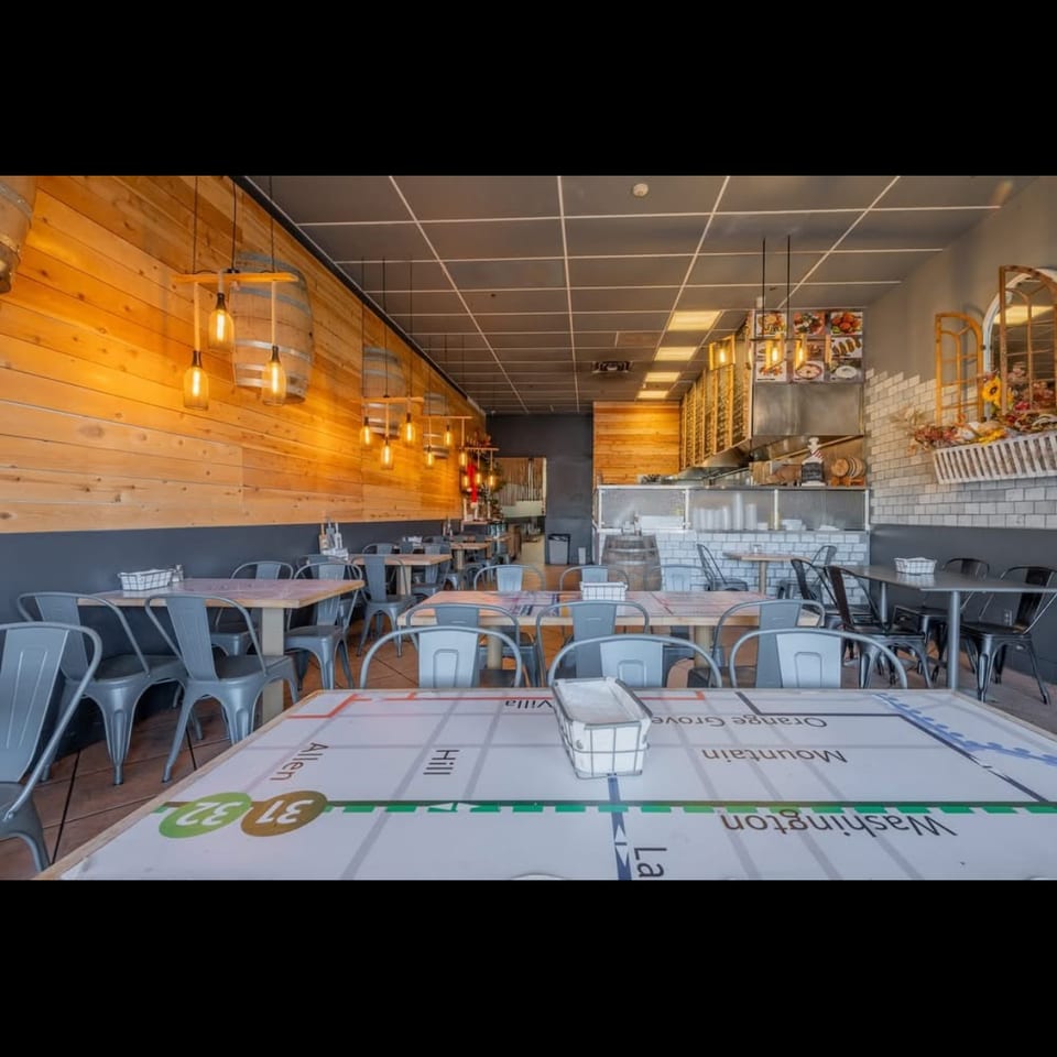 Interior view of a restaurant with wooden walls, industrial lighting, and tables with map-themed placemats.